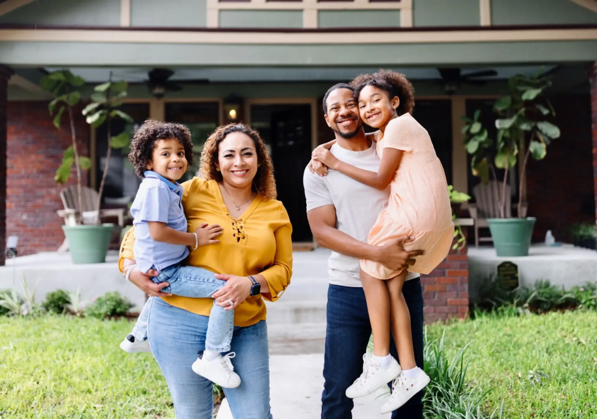 Happy family posing in front of house.