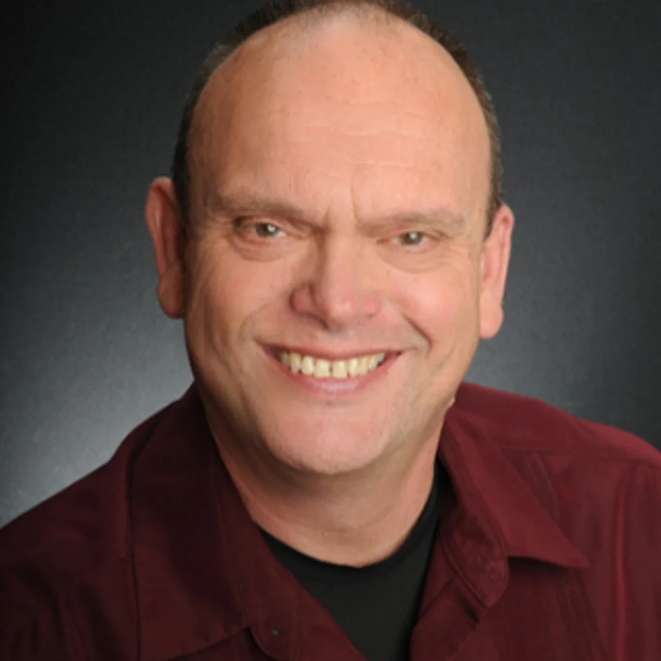 Smiling man in a maroon shirt.